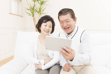 Evde dijital tablet kullanan yaşlı çift 