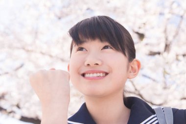 Sokakta çiçek açan kiraz ağaçlarıyla güzel Japon öğrencinin portresi.