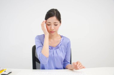 Başı ağrıyan genç bir kadın ofisinde oturuyor.