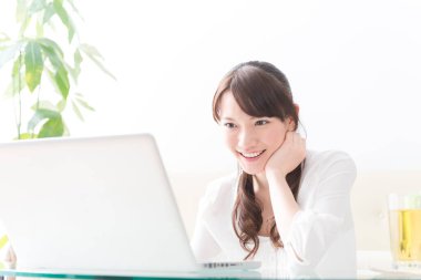 Evde dizüstü bilgisayar kullanan Asyalı genç bir kadın. 