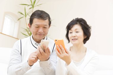 Yetişkin Asyalı çifti telefonları kullanarak kapatın.