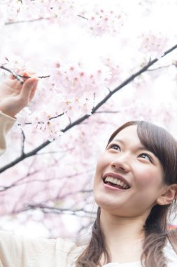 Japonya 'daki Sakura ağacında kiraz çiçekleri olan Asyalı kadın.