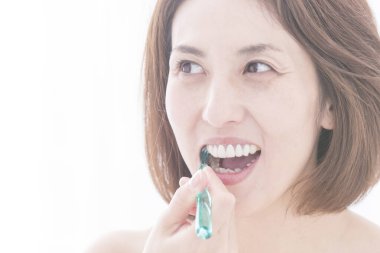 Güzel Japon kadın beyaz arka planda dişlerini fırçalıyor.