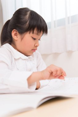 Küçük Asyalı kız ödevini yapıyor. 