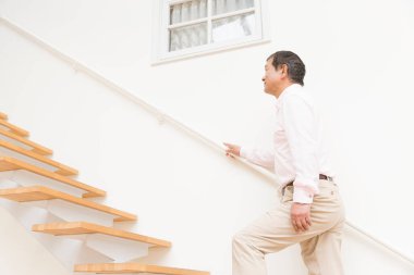 Üst düzey Asyalı beyaz gömlekli adam merdivenlerde yürüyor.