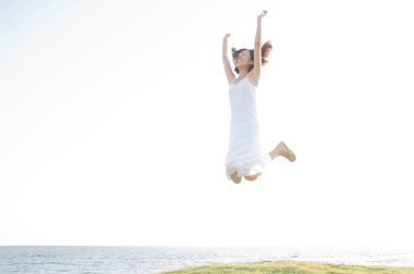 Okyanus kıyısında neşeyle atlayan bir kadın