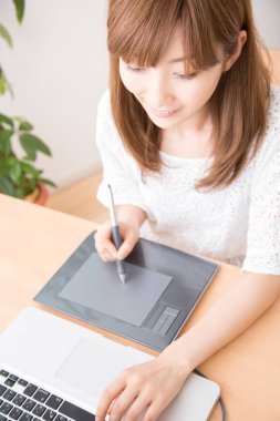 Dizüstü bilgisayar ve grafik tableti ile çalışan kadın grafik tasarımcısı