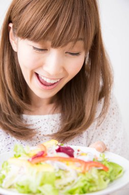 Gülümseyen Japon kadın taze salata tabağıyla