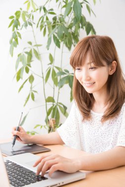 Dizüstü bilgisayar ve grafik tableti ile çalışan kadın grafik tasarımcısı