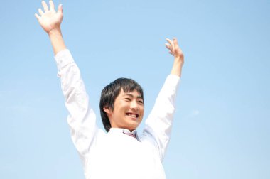 Elleri havada gülümseyen genç bir adam.