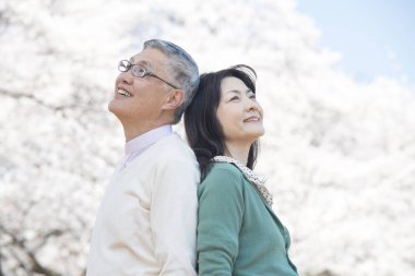 Güzel Asyalı olgun çifti ağaçlarla parka kapatın.