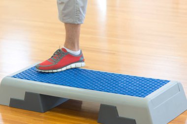 Fitness merkezinde egzersiz yapmak için stepper kullanan adam.