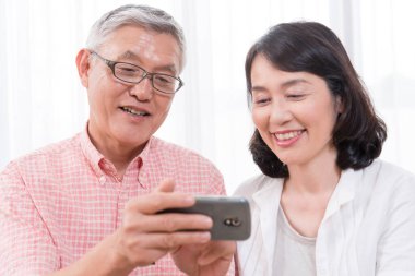 Evde akıllı telefon kullanan yaşlı bir çift. 