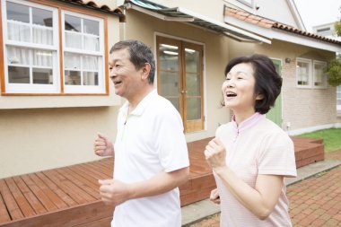 Asyalı bir adam ve kadın kaldırımda koşuyorlar.