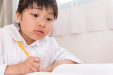 Küçük Asyalı kız ödevini yapıyor. 