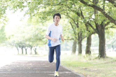 Sportif Japon adam yaz parkında koşuyor. 