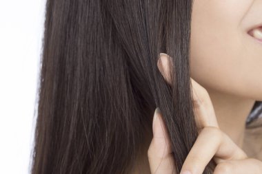 Uzun düz siyah saçlı, açık arkaplanda genç bir kadın..