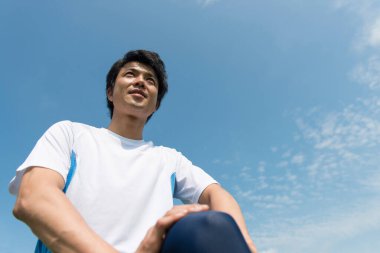 Genç Asyalı parkta geriniyor.