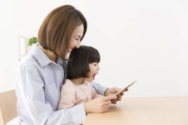 Tablet kullanan Asyalı bir kadın ve bir çocuk.