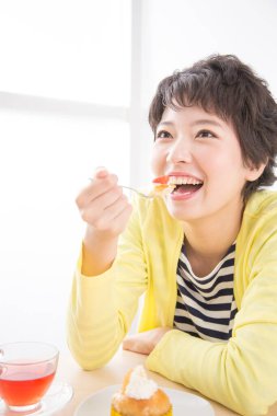 Asyalı kadın sabahları kahvaltı yapıyor.