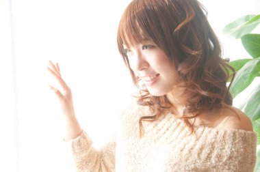 Odada pencereden bakan genç bir kadın.