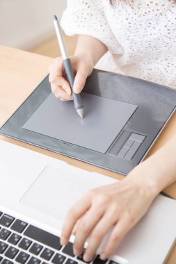 Dijital resim tableti ve dizüstü bilgisayar kullanan kişi