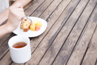 Kadın kek ve çayla kahvaltı yapıyor.