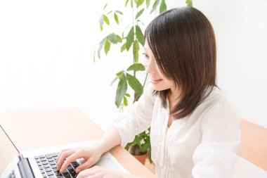 Evde dizüstü bilgisayarda çalışan Asyalı kadın.