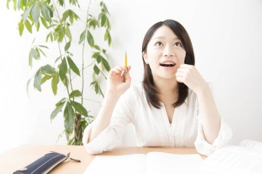 Genç Asyalı kadın evde ders çalışıyor.