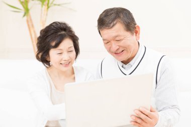 Evde dizüstü bilgisayar kullanan yaşlı çift. 