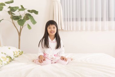 Genç Asyalı kadın evde yatakta ne yapıyor?