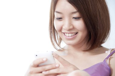 Evde dinlenirken akıllı telefon kullanan güzel bir Japon kadının portresi.