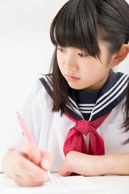 Okul üniformalı gülümseyen Japon öğrenci okulda ders çalışıyor.