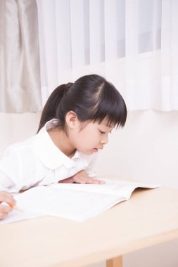Küçük Asyalı kız ödevini yapıyor. 
