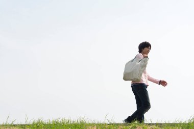 Asyalı adam yeşil çayırda yürüyor.