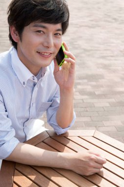 Deniz kıyısında cep telefonu kullanan Asyalı adam.