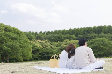 Dört kişilik Asyalı aile parkta piknik yapıyor.