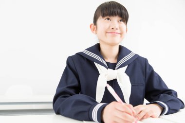 Okul üniformalı gülümseyen Japon öğrenci okulda ders çalışıyor.