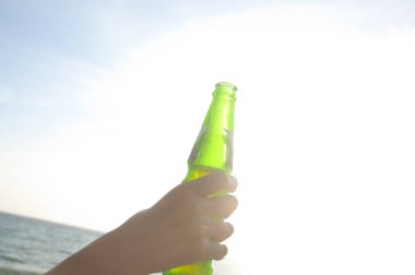 El ele tutuşan bira şişesi.