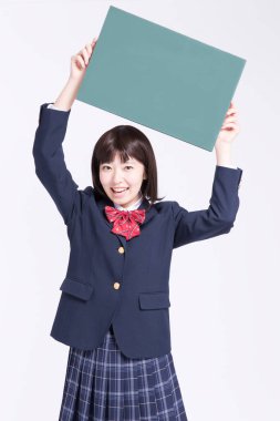 Genç Asyalı kız beyaz arka planda boş yeşil tahta gösteriyor.