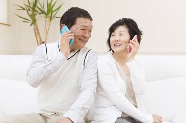 Yetişkin Asyalı çifti telefonları kullanarak kapatın.