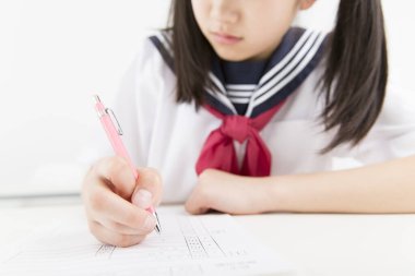 Okul üniformalı gülümseyen Japon öğrenci okulda ders çalışıyor.