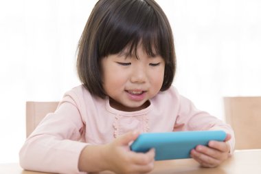 Küçük sevimli Asyalı kız telefon kullanıyor.