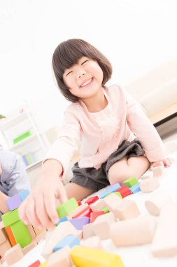 Küçük sevimli Asyalı kız tahta oyuncak bloklarıyla oynuyor.