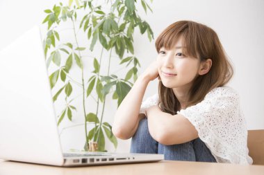 Evde dizüstü bilgisayarı olan gülümseyen güzel bir Japon kadın.