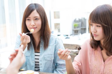 Genç Asyalı kadınlar tatlı yiyor.