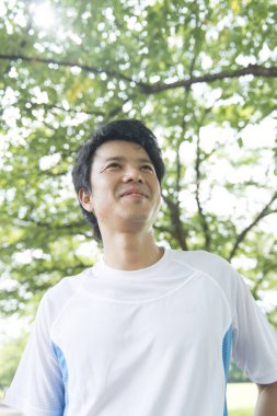 Sportif Japon adam yaz parkında koşuyor. 