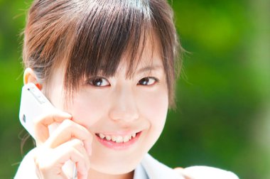 Akıllı telefon kullanan Asyalı genç bir kadının portresi. 