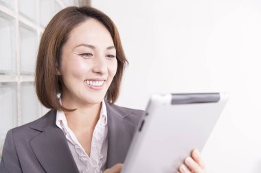 Ofiste tablet kullanan takım elbiseli Japon iş kadını.