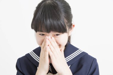 Asyalı genç bir kızın portresi. Üniformalı ve yüzünde elleri olan.